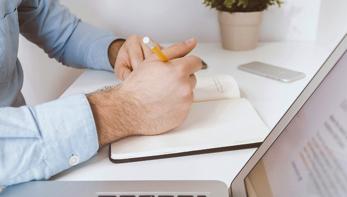 Close-up of a man writing in a notebook.