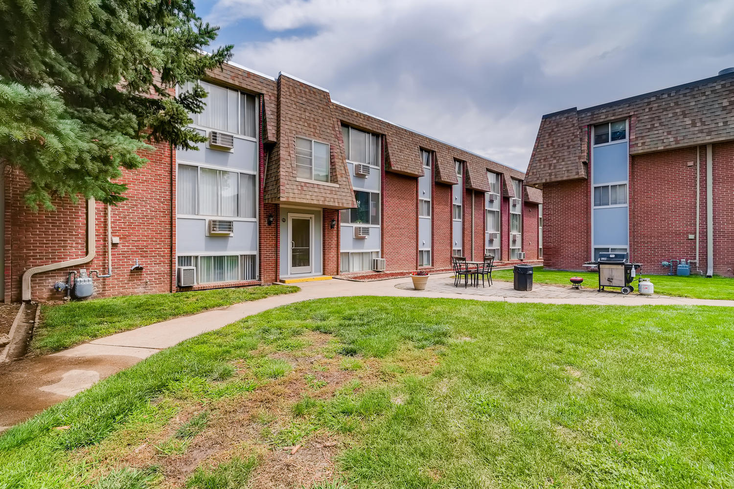 Courtyard lawn and grilling area with gas grill, picnic table, and brick building exterior.