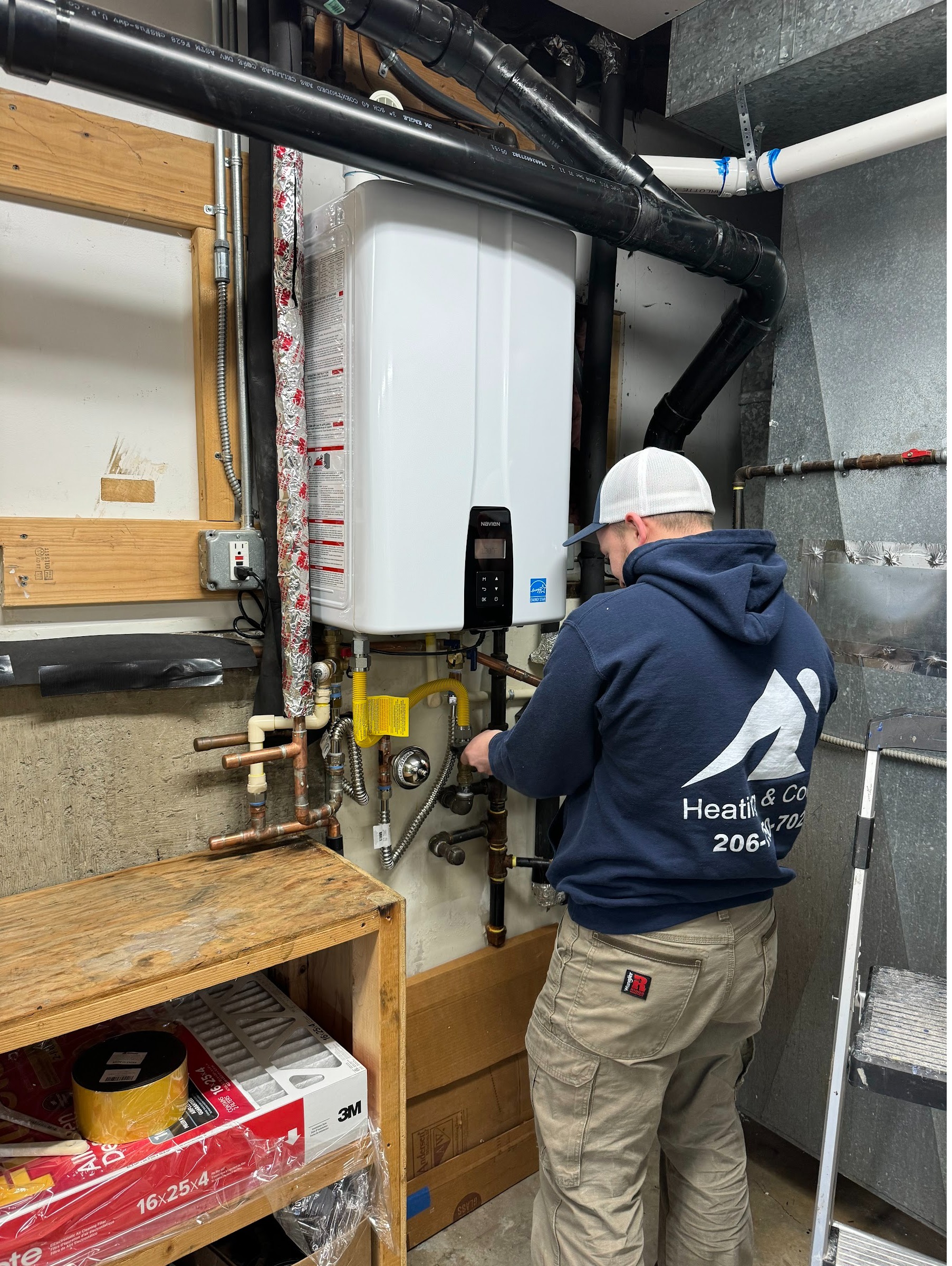 Ready Energy Solutions technician installing a wall-mounted tankless water heater. Tankless water heater installation and replacement in Greater Seattle.