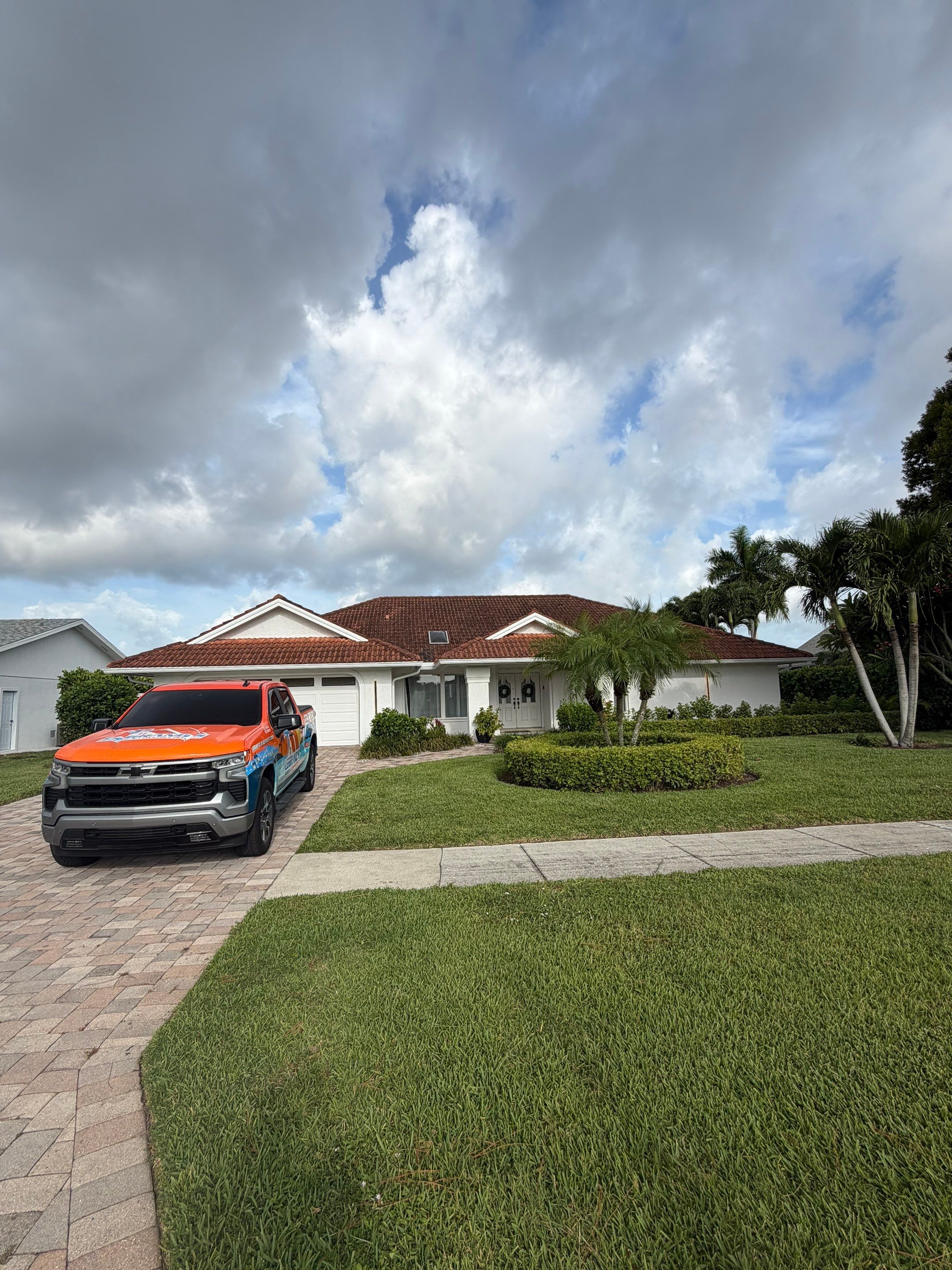 Roofing company vehicle positioned in front of a completed residential roof and well-maintained prop 