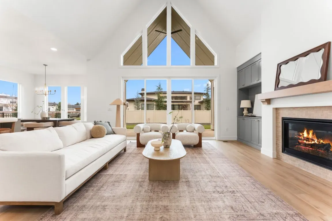 The open living space showcases premium flooring, soaring ceilings, custom ceiling treatments, and a dramatic 48-inch Napoleon gas fireplace.