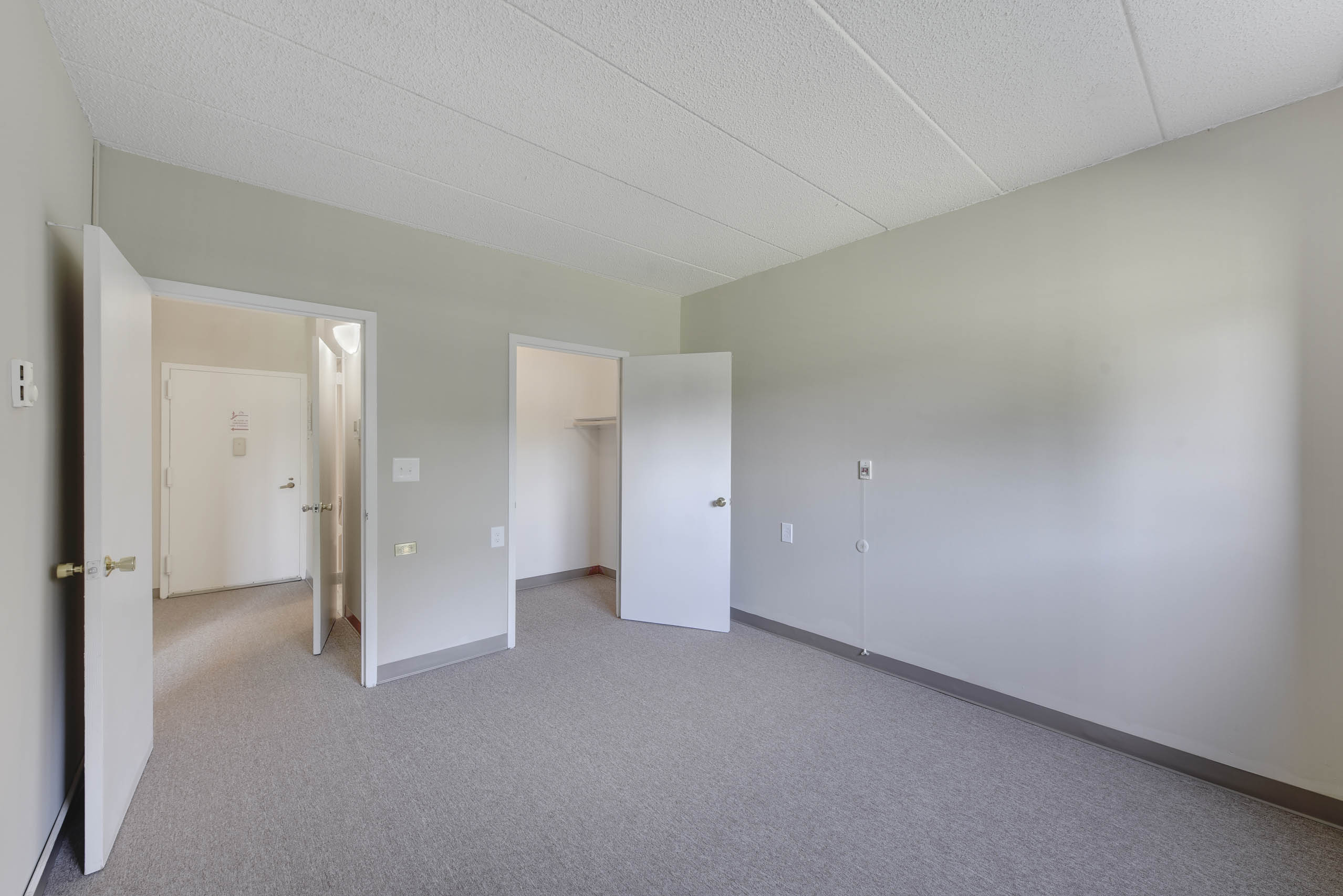 A large empty room with carpeted floor and white walls.
