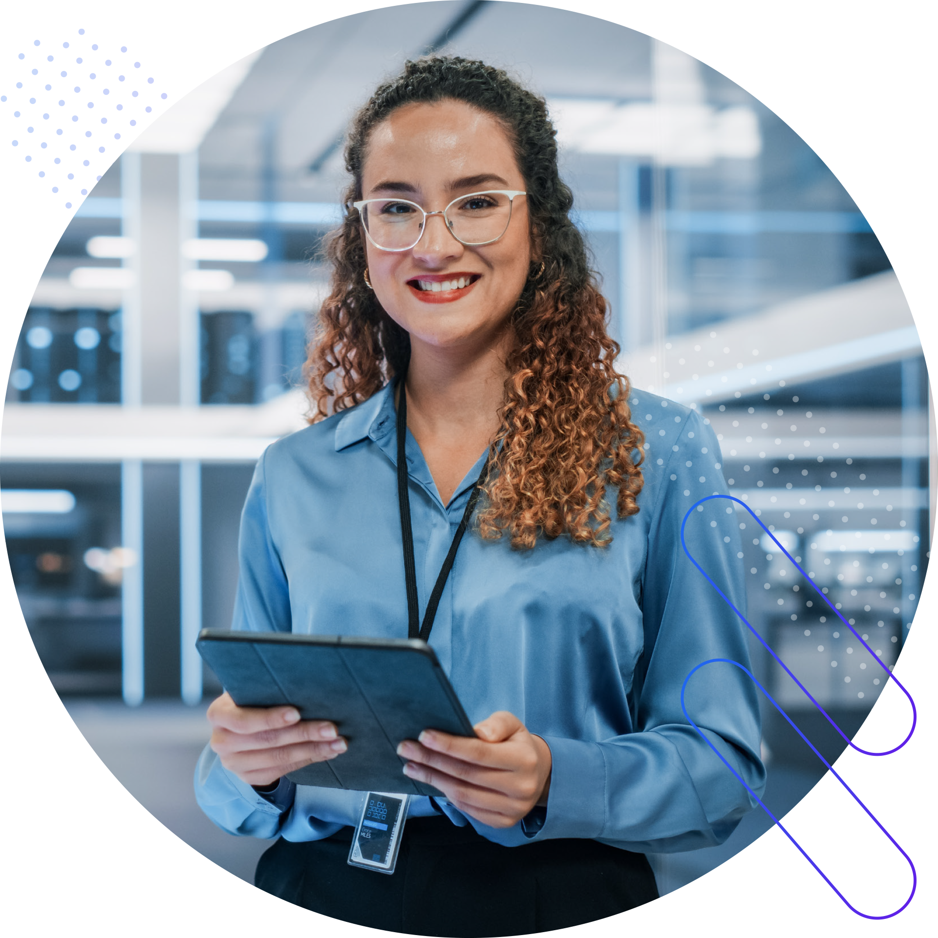 A smiling woman with curly hair and glasses stands in a modern office environment, holding a tablet. She is wearing a blue button-down shirt and a lanyard with an ID badge. The background appears to be a server room or data center, with blurred rows of equipment. The image is framed within a circle with decorative dots and lines.