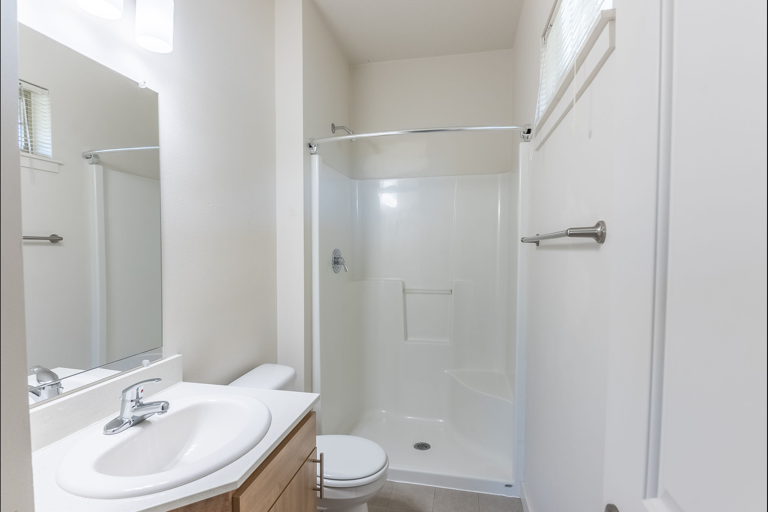 A white bathroom with a toilet, sink, and shower.