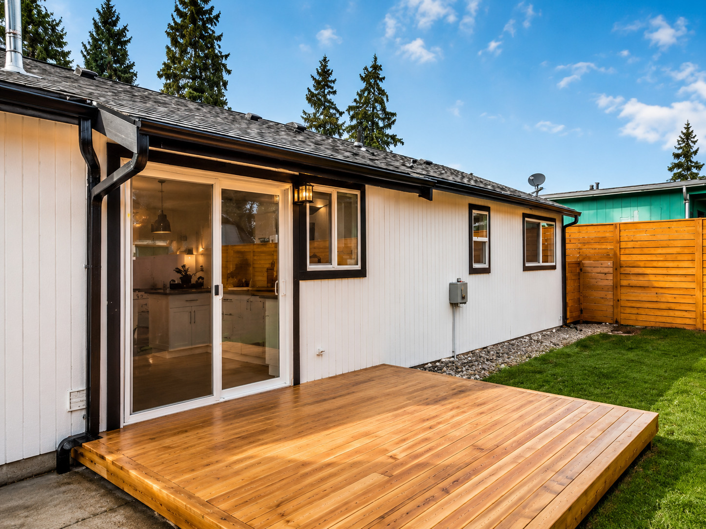 A freshly built wooden deck extends from a home's sliding glass doors, creating a warm outdoor livin 