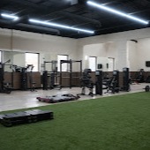 Versatile indoor training facility featuring artificial turf and functional fitness equipment. Our modern performance zone supports athletic training, strength conditioning, and dynamic movement exercises in a spacious, professionally-lit environment.