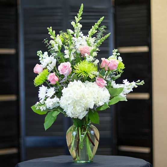 Elegant white hydrangeas, pink roses, white snap dragons and green spider mums are arranged in a ginger vase. Inspired by the quiet beauty of nature our hand designed arrangement is a showy gift for any occasion.