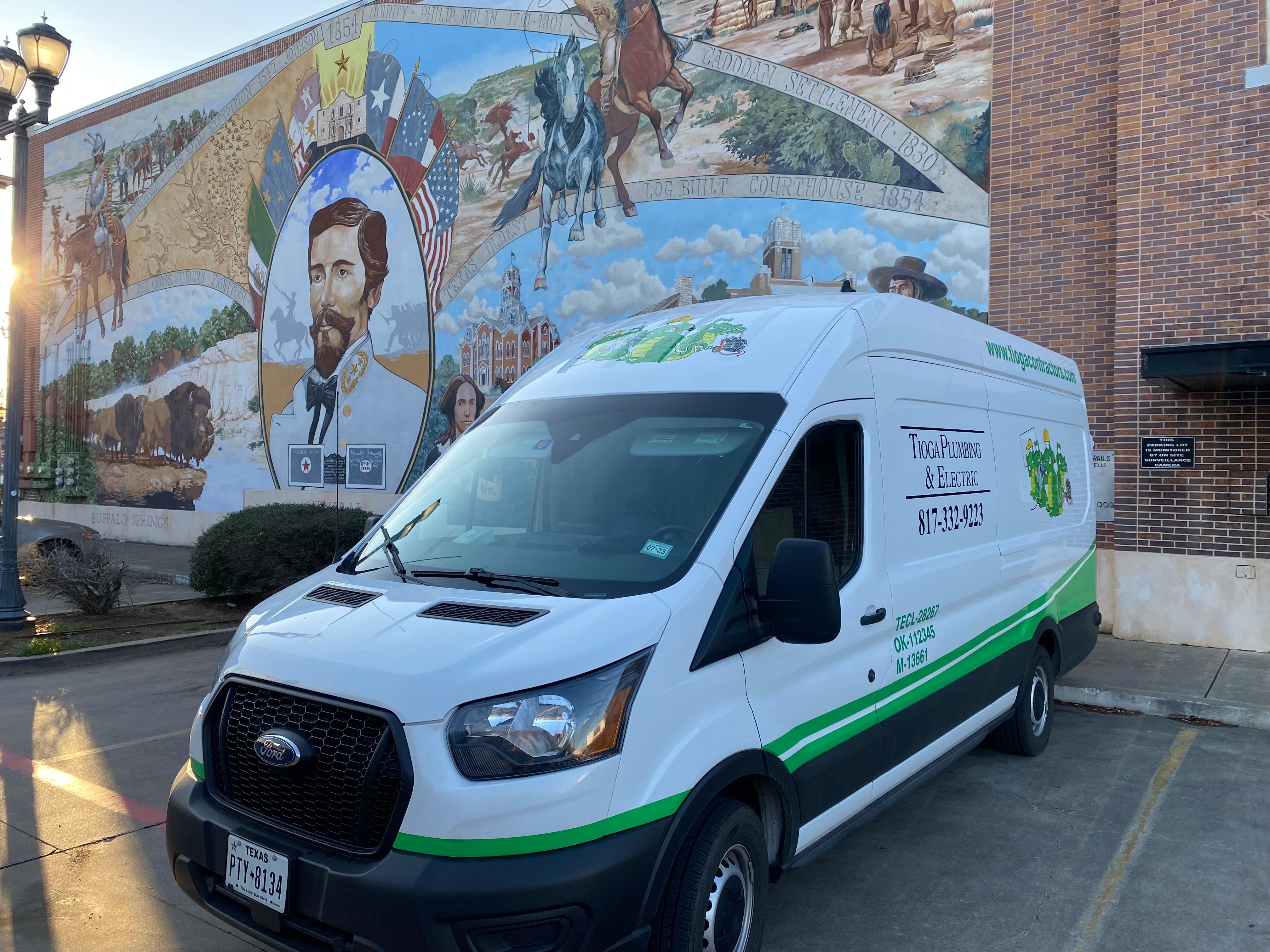 A Tioga Plumbing & Electric service van in front of the Murals of Cleburne in Wright Plaza in Cleburne Texas.