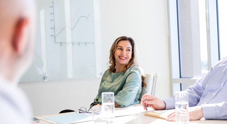 Smiling woman sitting at a boardroom table.