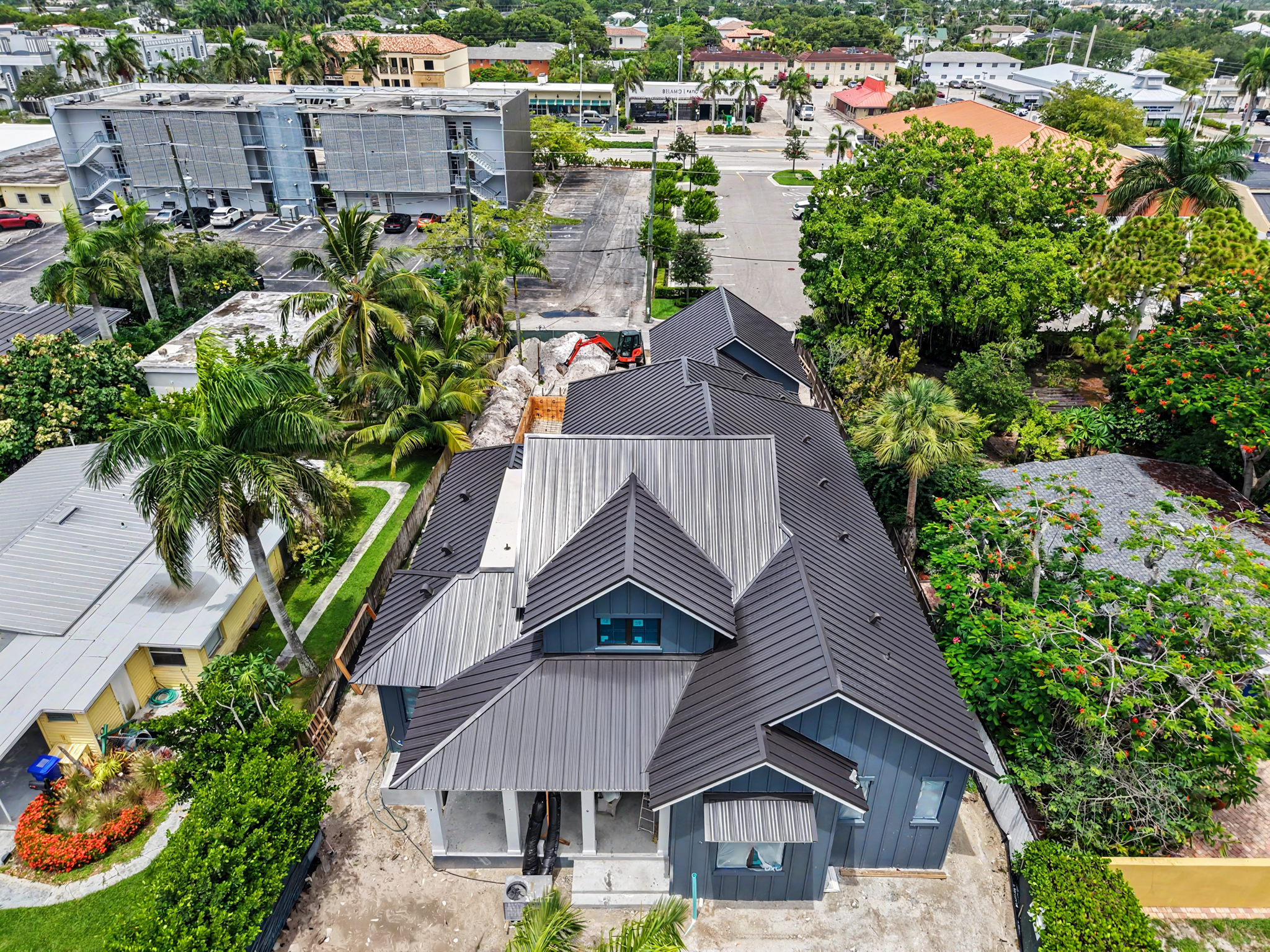 Front aerial view of a newly constructed home featuring a dark standing seam metal roof with multipl 