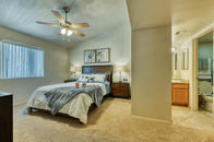 Bedroom with ceiling fan, vaulted ceiling, and view to bathroom with cherry cabinets and tile.