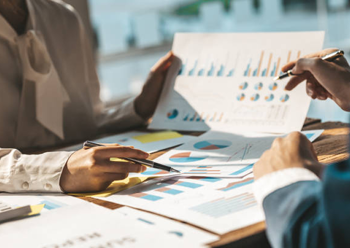 Close-up of a client two professionals reviewing charts.