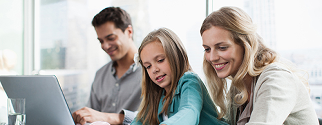 Father, mother and young daughter working at a table together.