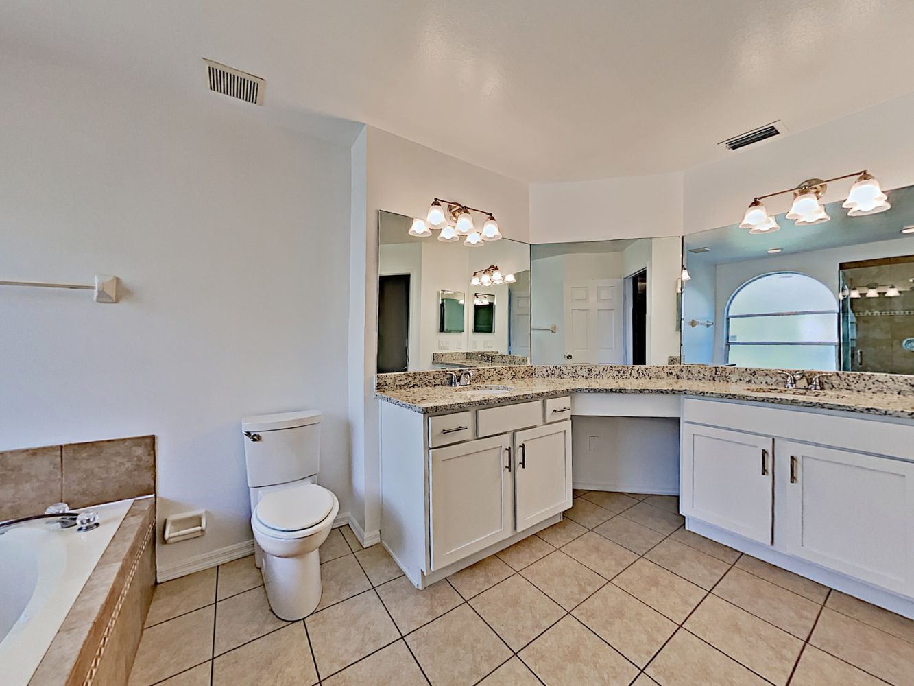 Large primary bathroom with relaxing tub and plenty of storage at Invitation Homes Orlando.