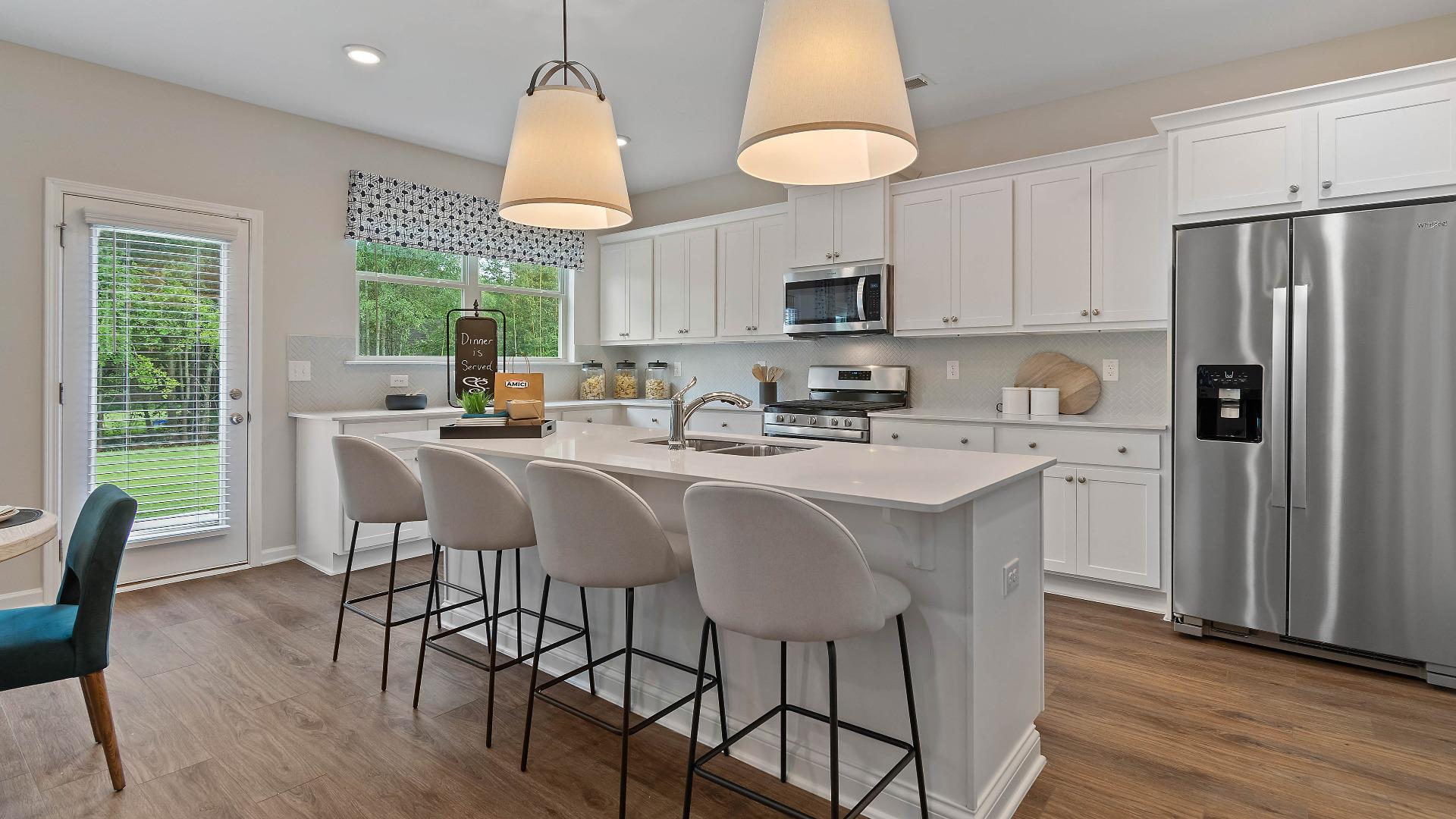 Single family home kitchen with white cabinets and island in DRB Homes Eleanora Community