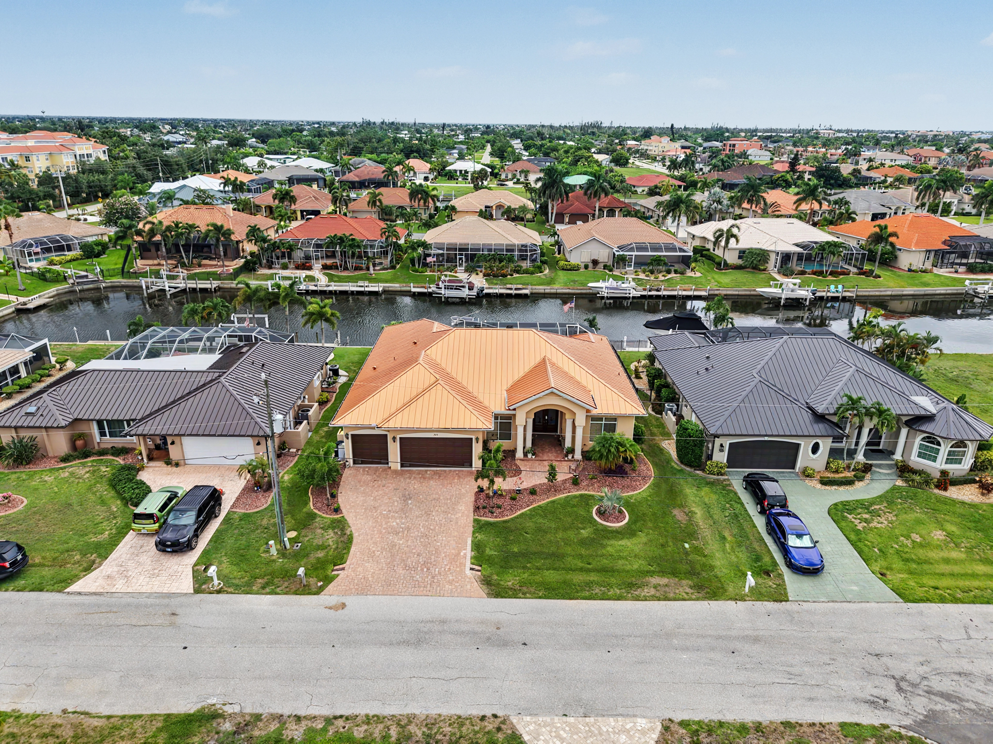High drone view of a waterfront home featuring a copper-colored standing seam metal roof within a co 