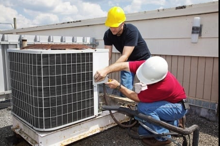 Two HVAC contractors are seen performing routine annual maintenance on a commercial HVAC unit. They are inspecting the unit, cleaning components, and ensuring its optimal performance. Their professional demeanor and attention to detail highlight the importance of regular maintenance for commercial HVAC systems.