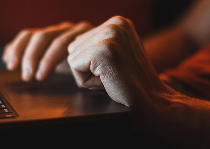 Closeup of a person's hands resting on their open laptop.
