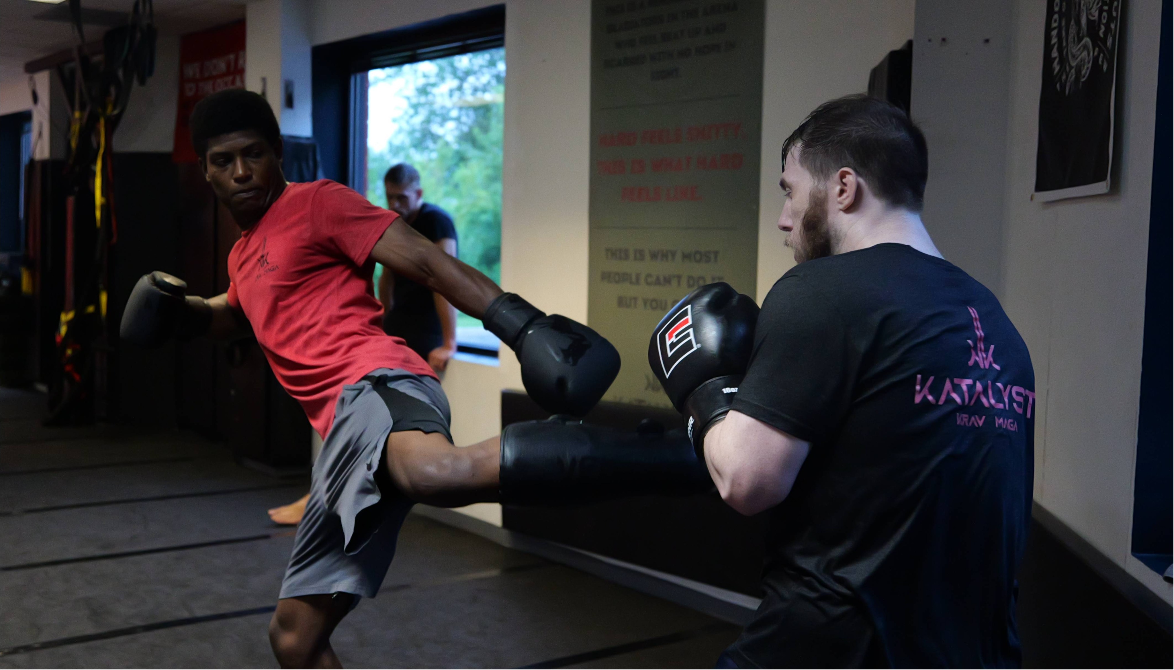 A student throwing a kick during partner drills on the mats at Katalyst Kombatives.