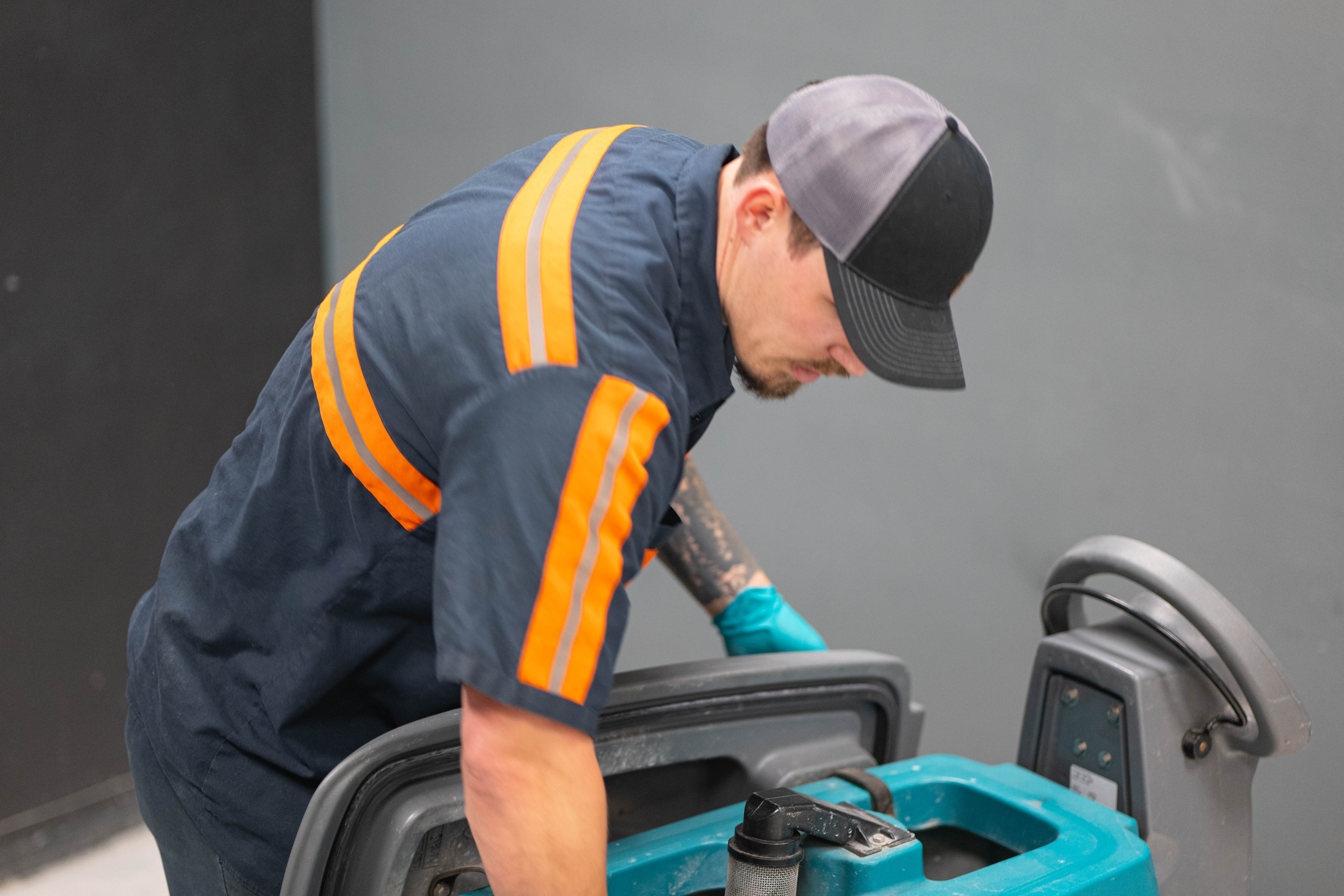 Professional technician conducting an on-site mechanical inspection and diagnostics check on a commercial walk-behind floor scrubber.