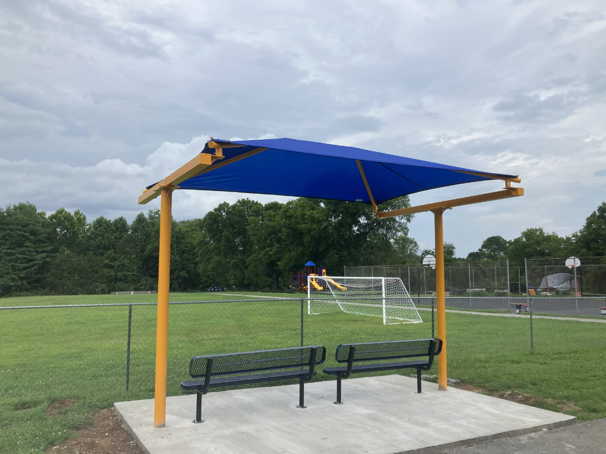 Blue cantilever shade structure over park benches.