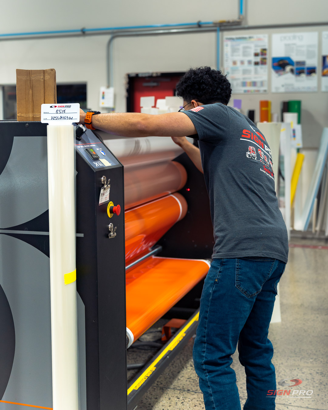 A Sign Pro team member operates a wide-format laminator to finish vibrant vinyl graphics, part of the company’s vehicle wrap and signage production services.