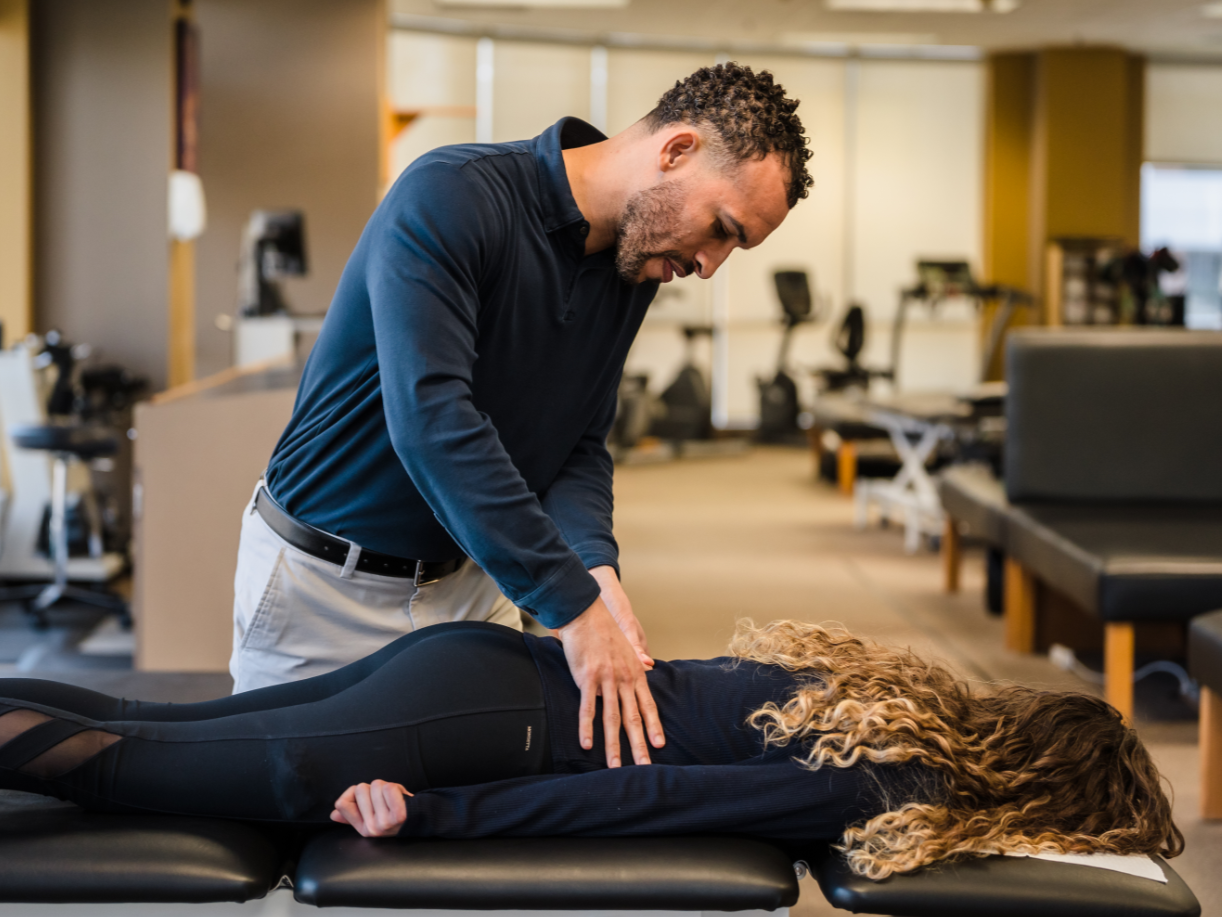 Therapist examining patient's lower back Select Physical Therapy - Tulsa - South Yale Tulsa (539)235-0170