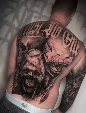 Eisenherz Tattoo und Piercing Magdeburg - Black and Grey Backpiece mit Totenköpfen, Augenbinden und großem Schriftzug über dem oberen Rücken. Dunkles Skull Tattoo für Keywords wie Rücken Tattoo, Skull Tattoo, Backpiece, Black and Grey Tattoo und gro...