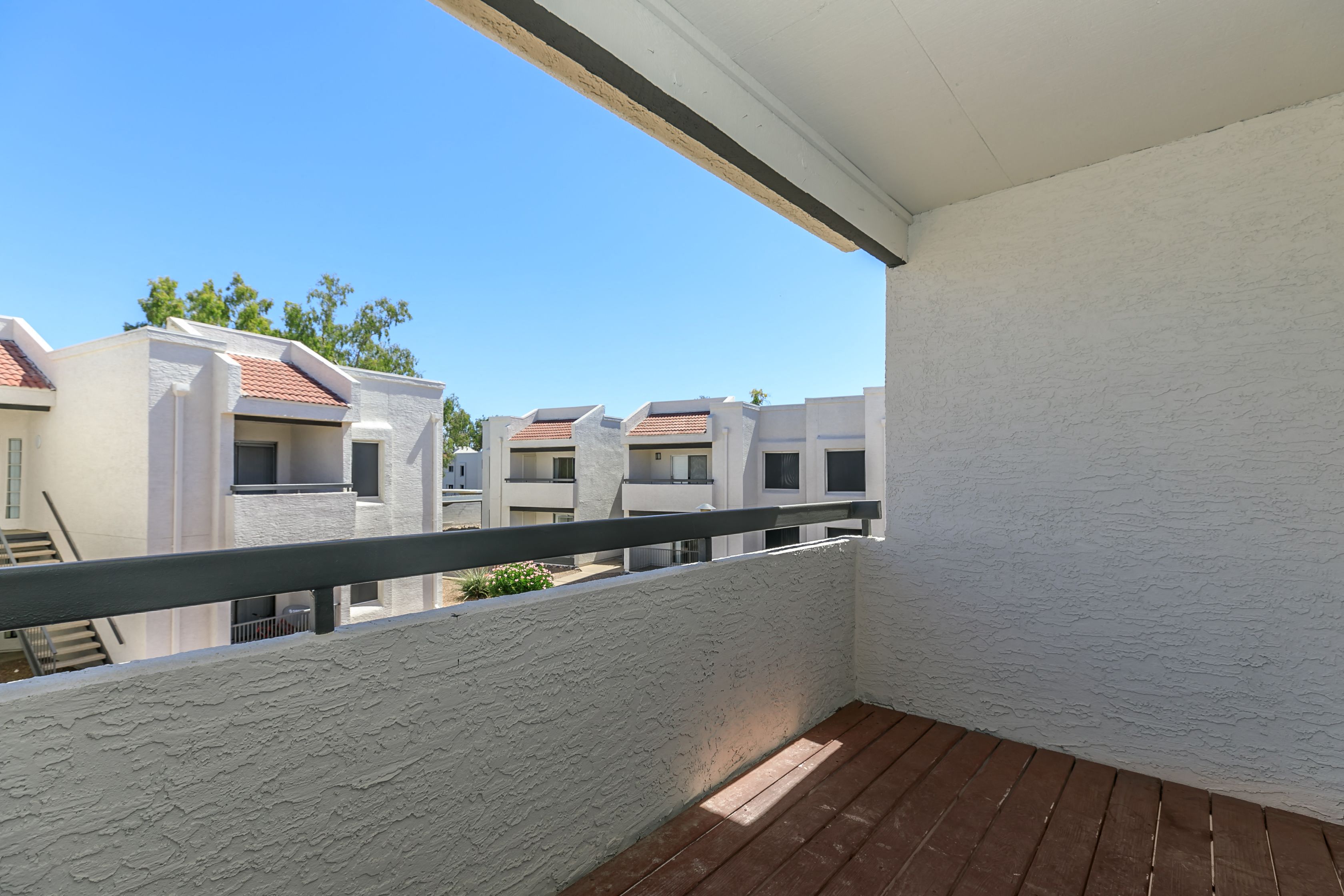 a balcony or terrace with a wood floor and a white wall
