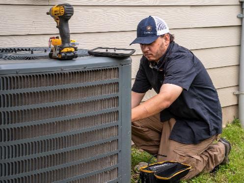 HVAC tech inspecting an outdoor HVAC system