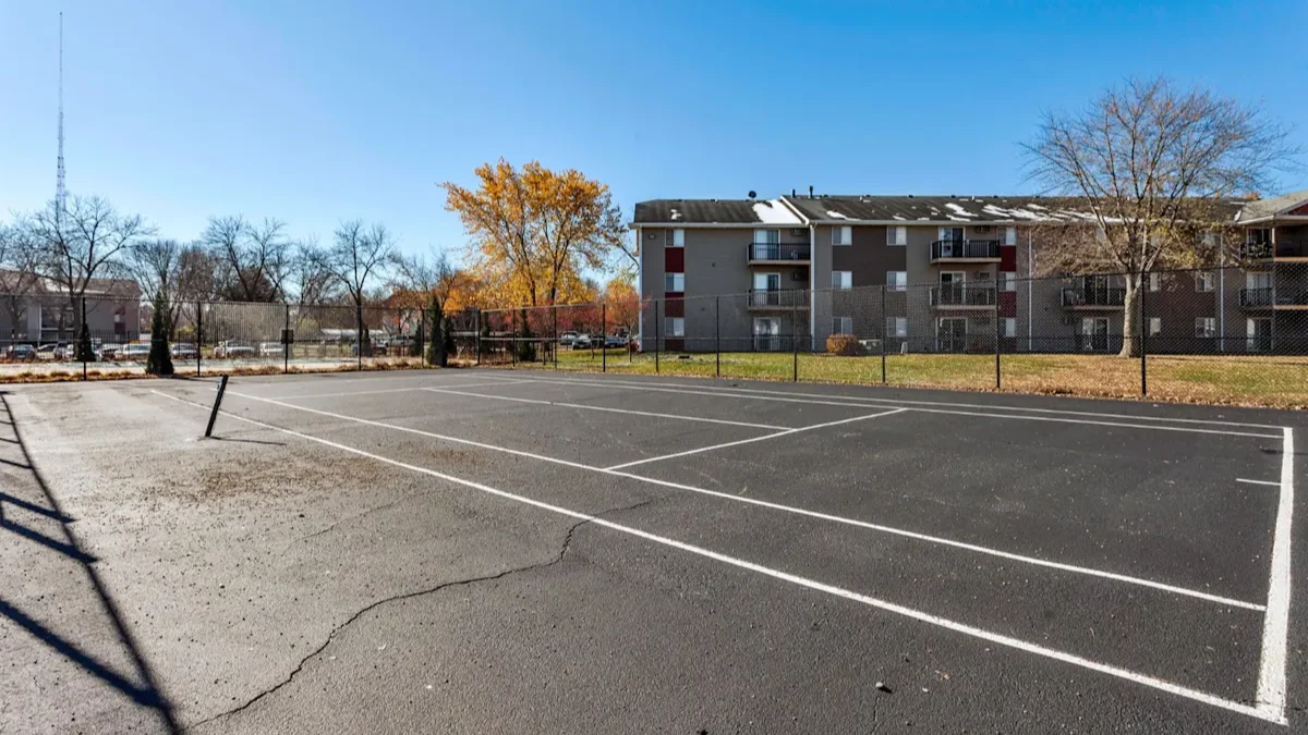 an empty parking lot with an apartment building in the background