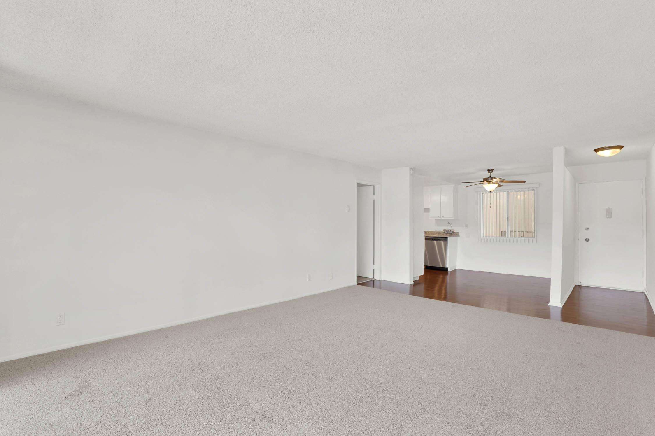 an empty living room with white walls and a ceiling fan