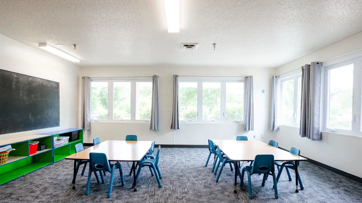 a classroom with tables and chairs and a chalkboard on the wall