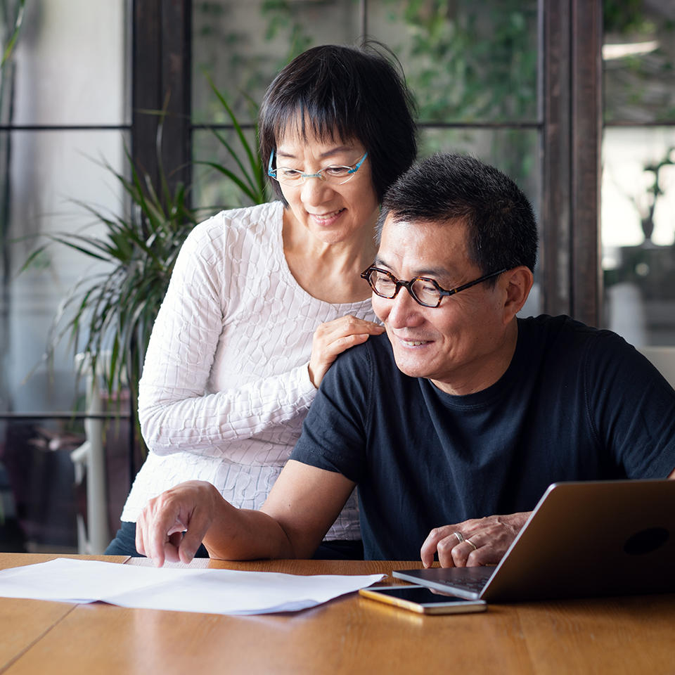 Senior couple looking at a piece of paper on a desk.