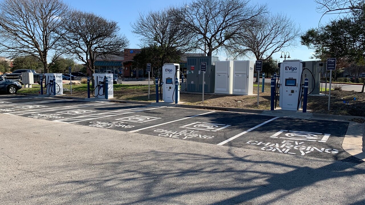 Several EVgo fast charging units installed in marked parking spaces at a public charging station, wi 