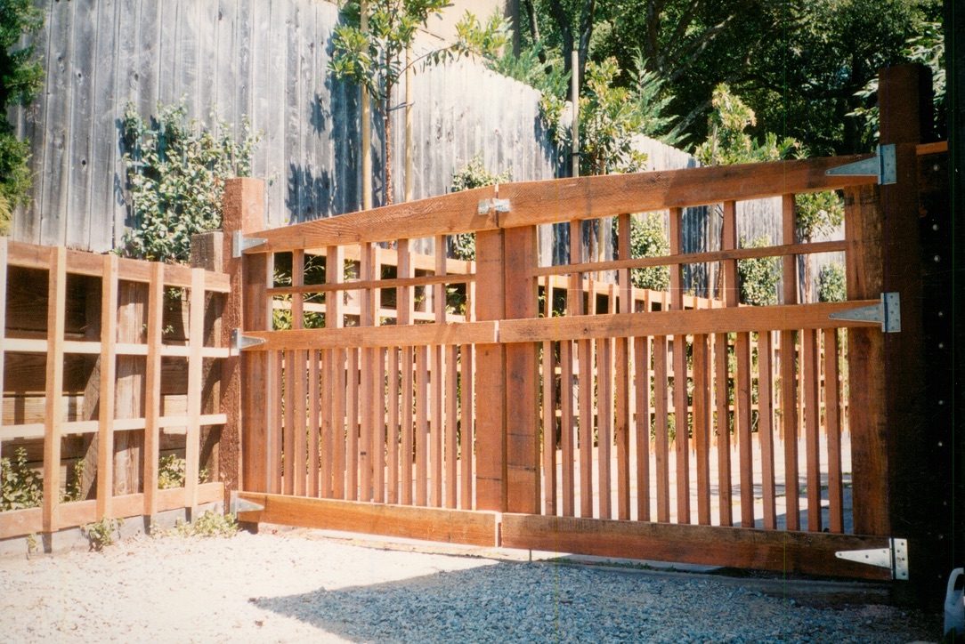 Custom wood driveway gate and fence installation providing secure access and enhanced curb appeal for a residential property.