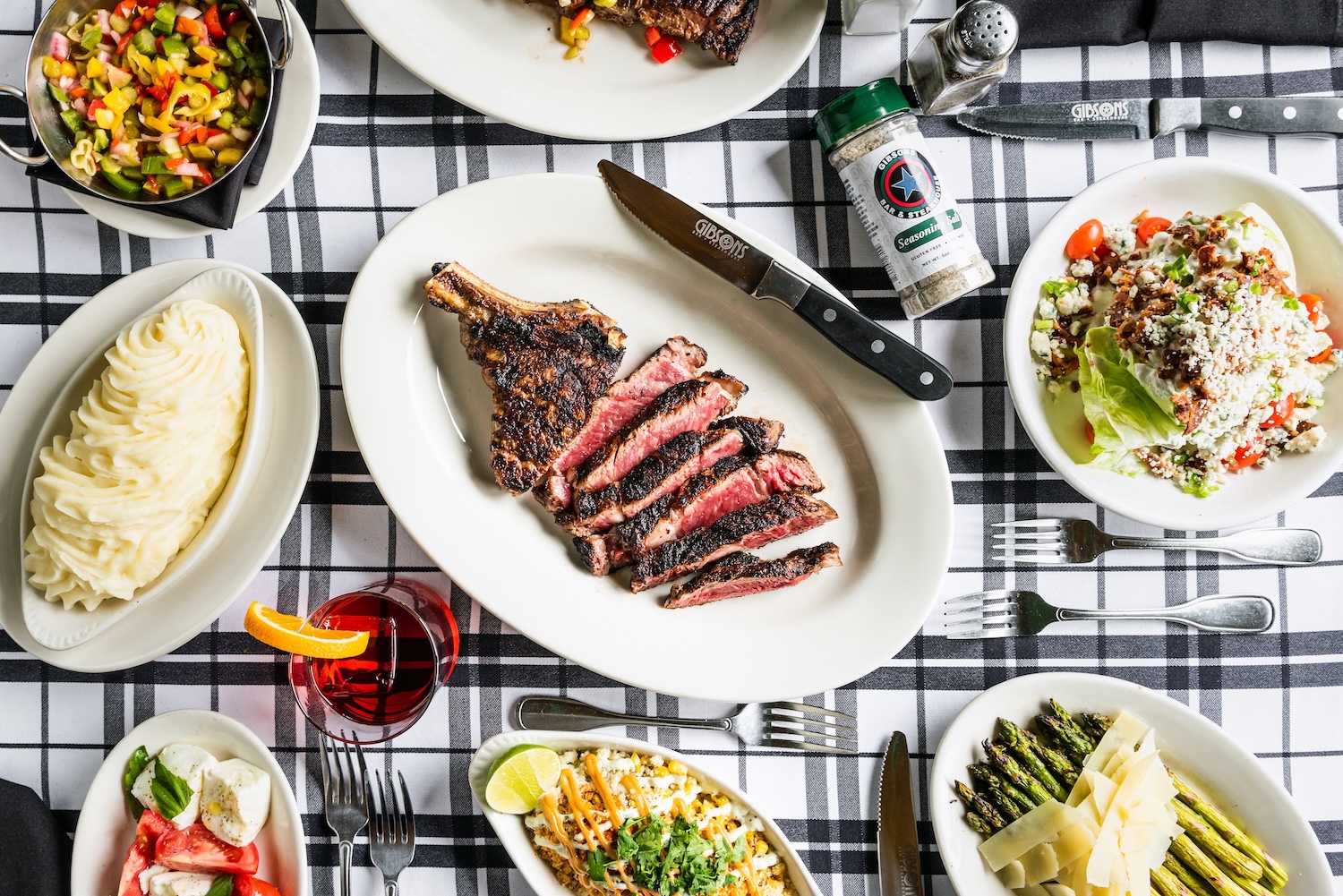 A perfectly seared W.R.'s Chicago Cut steak, Gibsons' signature bone-in ribeye, presented in a class 