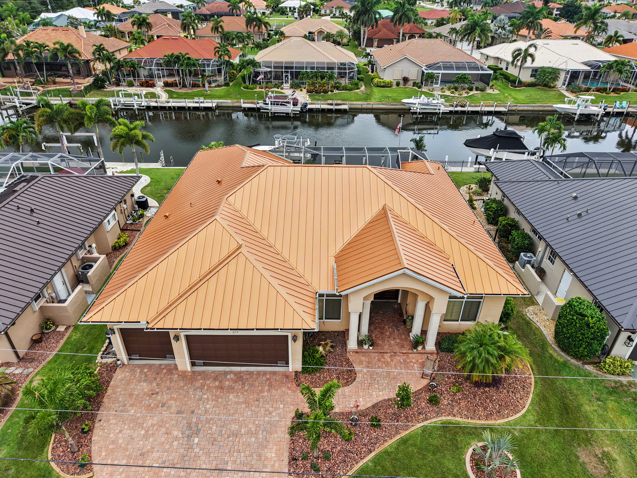 Aerial view of a waterfront home featuring a newly installed copper-colored standing seam metal roof 