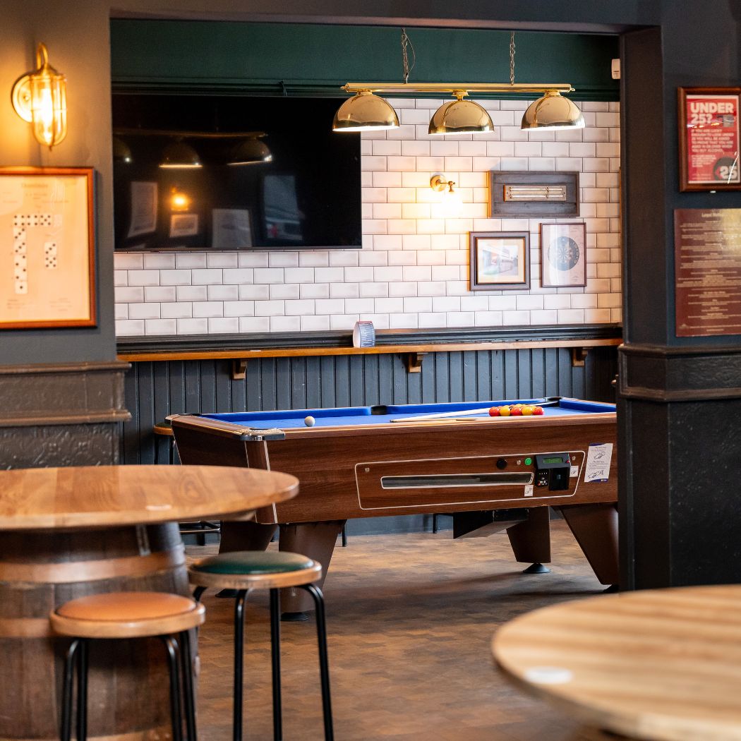 Pool table area with overhead lighting and a wall-mounted screen, perfect for casual games and watching sport.