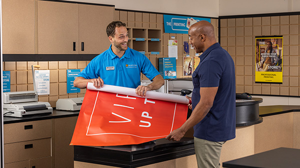 associate showing event banner to customer in the ups store