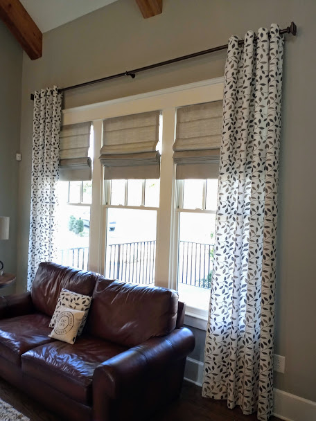 We loved this project! Our customer was looking for beautiful window treatments that would let in a lot of light and also dress up her space. We absolutely love the cozy, rustic feel of the leather sofa with the soft patterns of her roman shades and drapery - and that custom pillow! made to