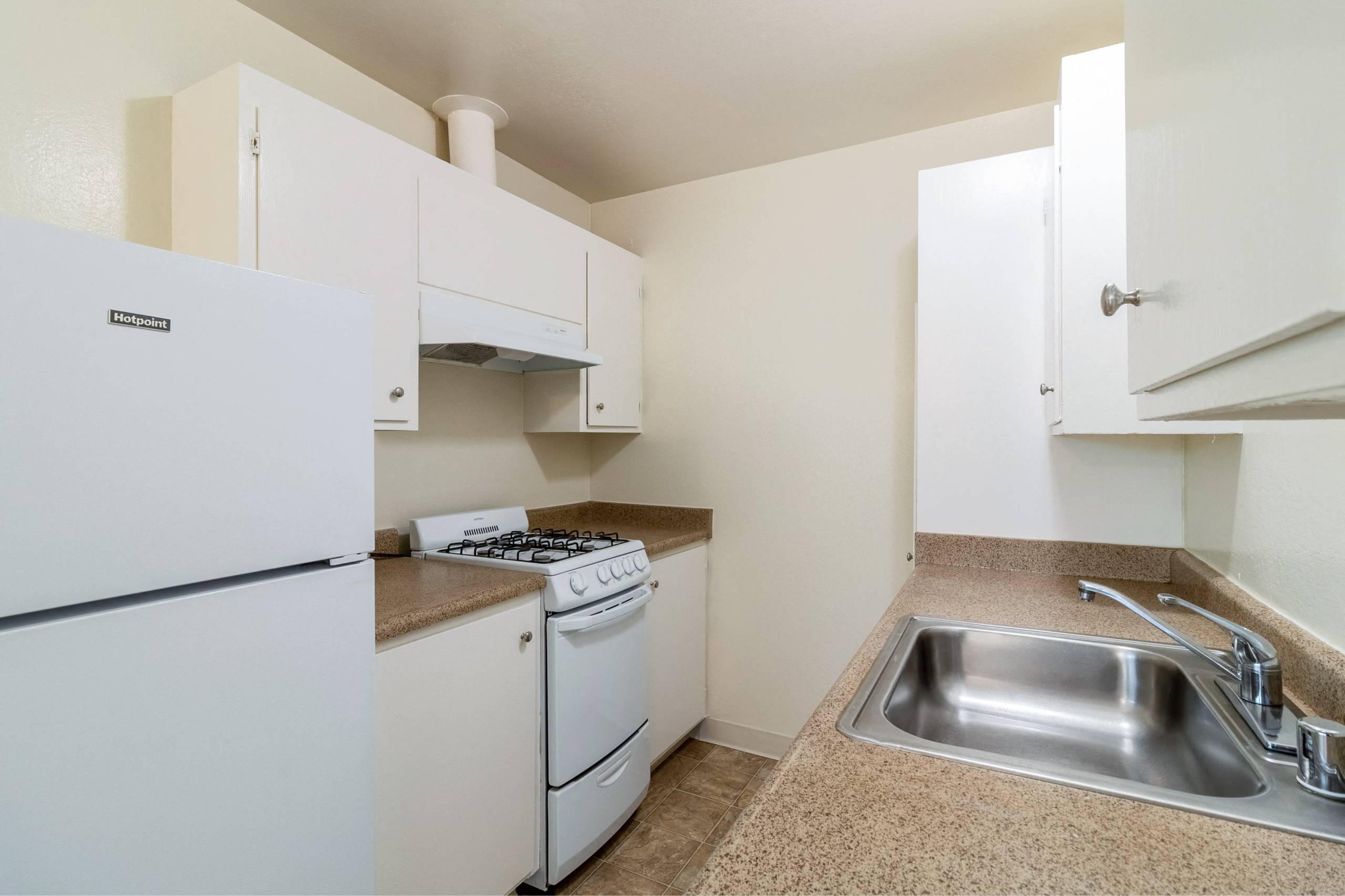 A kitchen with a white fridge, stove, and sink.