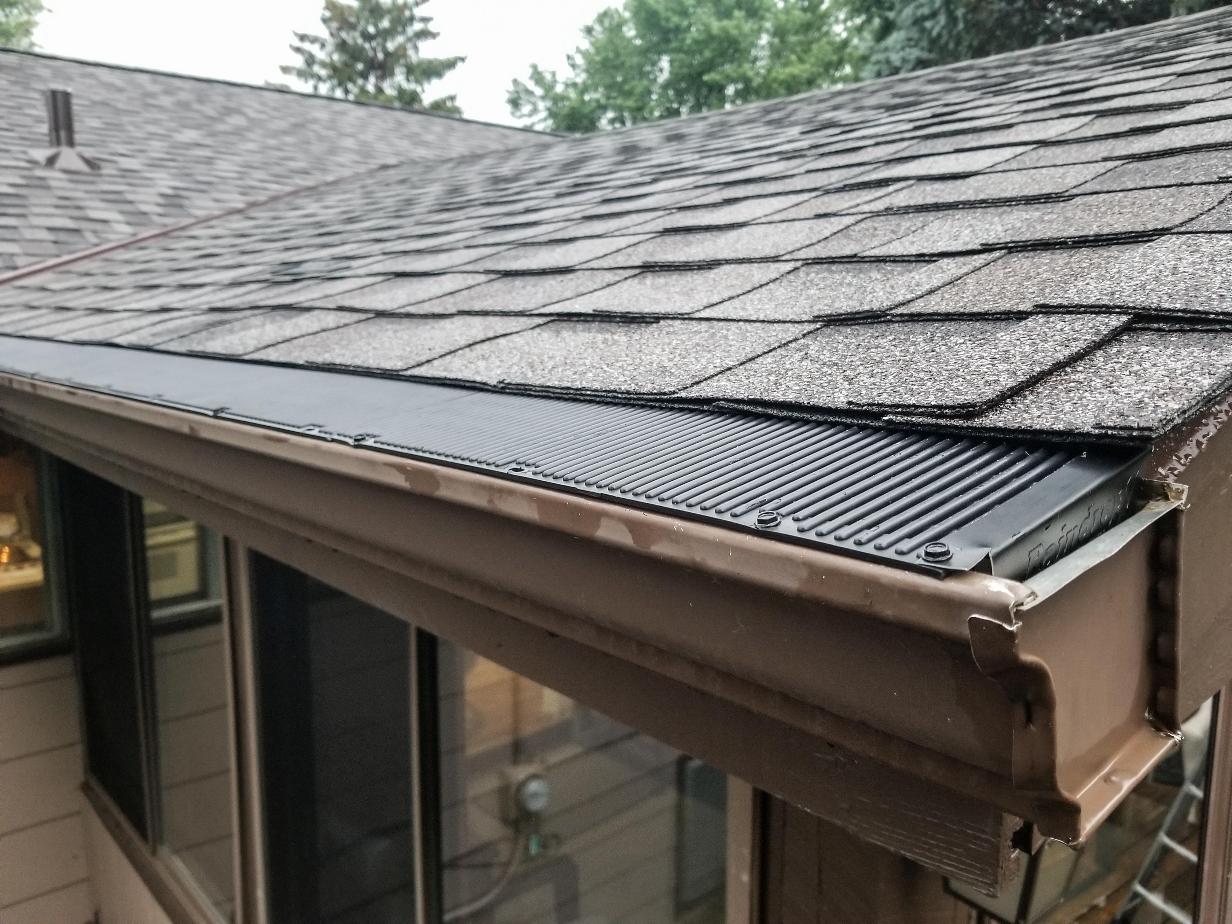 Brown seamless gutter with a black ribbed gutter guard installed by Ultimate Gutter Solutions.