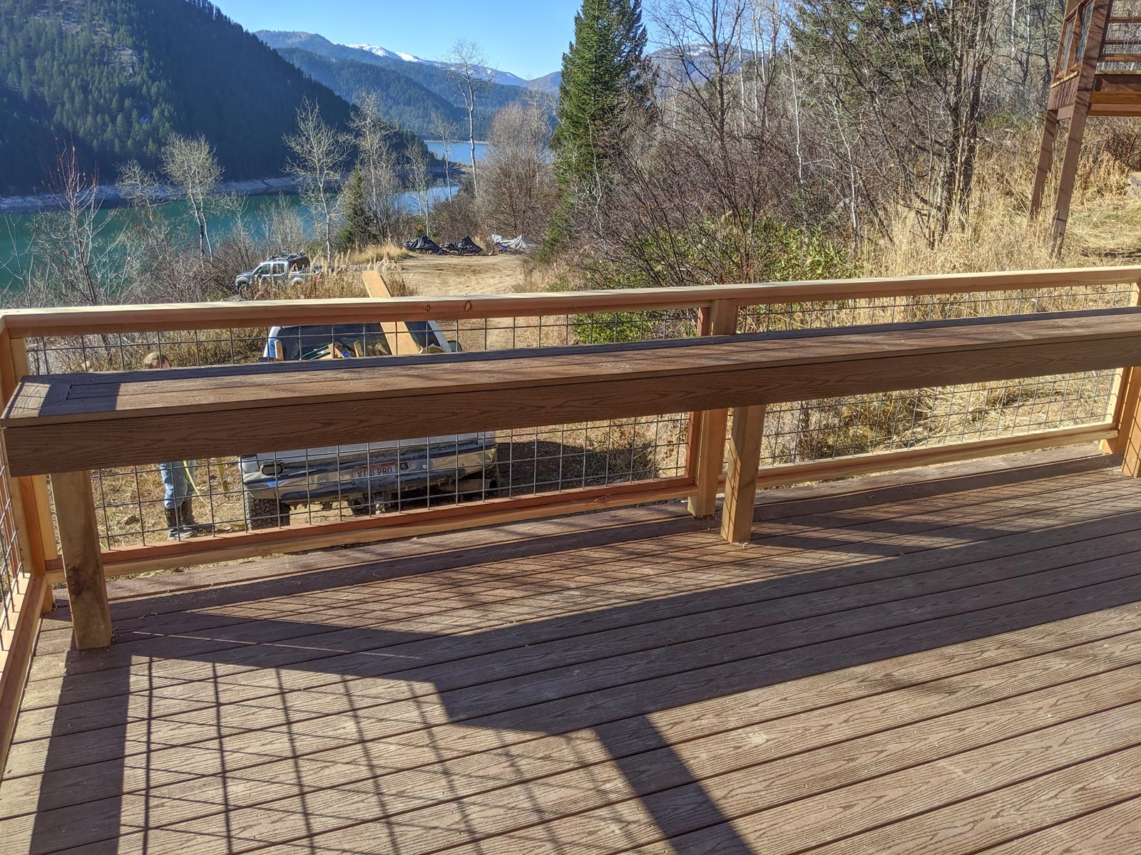 Take in the stunning mountain views from this custom composite deck by DeckPro LLC. This project combines rustic and modern elements, featuring a long, built-in wooden bench for ample seating and a durable wood frame railing with industrial wire mesh infill that keeps the beautiful scenery unobstructed.