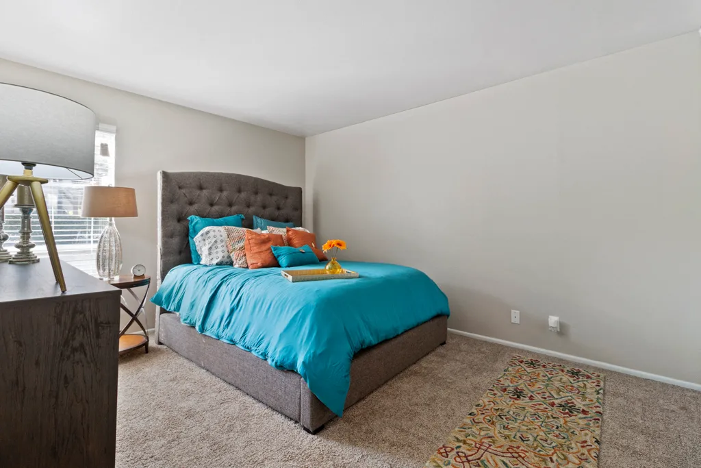 Bedroom with tufted headboard and colorful accent rug