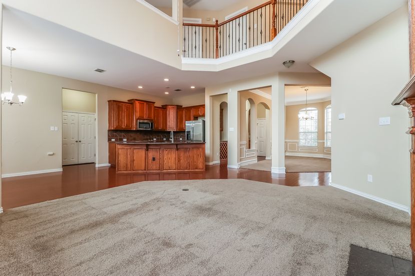 Spacious family room with tall ceilings and a fireplace at Invitation Homes Houston.