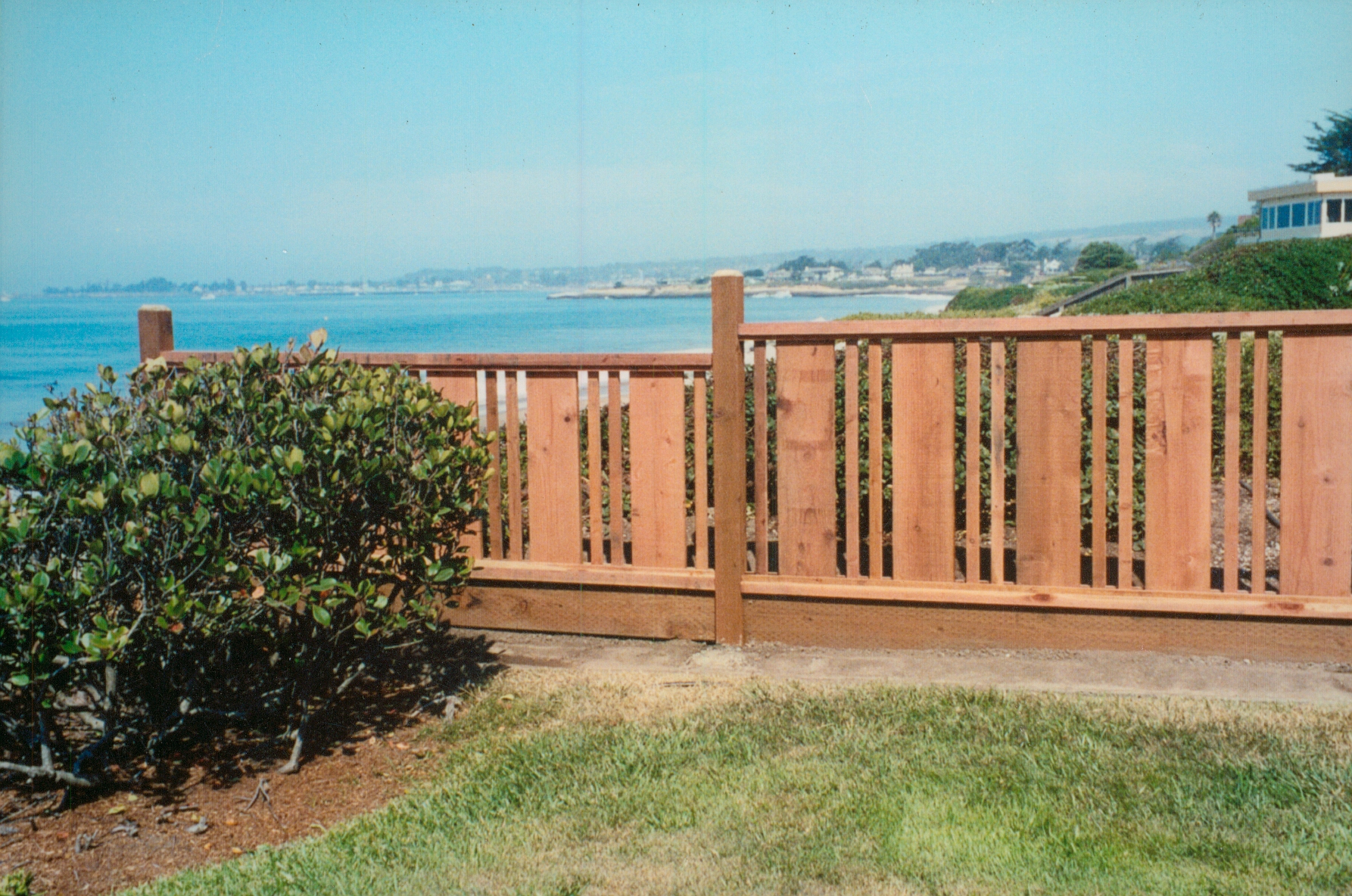 Custom wood fence installation overlooking a coastal property, providing privacy and a clean finished look.