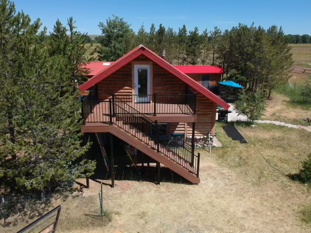 Designed to blend seamlessly with its rustic surroundings, this custom composite deck by DeckPro LLC is the perfect addition to this Idaho log cabin. The project features durable decking, sleek black metal railing, and a staircase for easy backyard access.