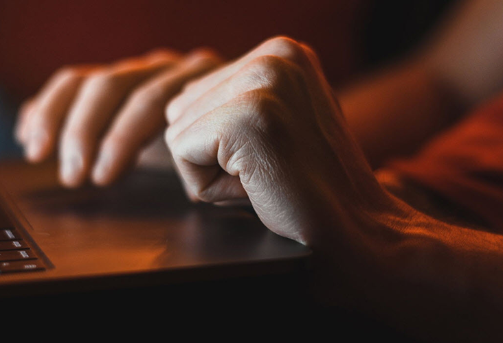 Closeup of a person's hands resting on their open laptop.