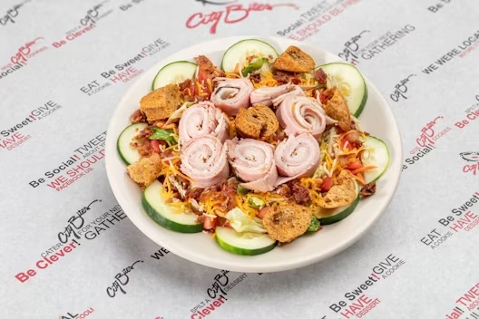 Ham, turkey, bacon bits, lettuce mix, shredded cheddar, tomatoes, cucumbers, shredded carrots & sun-dried tomato croutons.